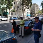 Three volunteers standing on a Tenderloin street. One is holding a speed radar device and another is writing information down in a clipboard.