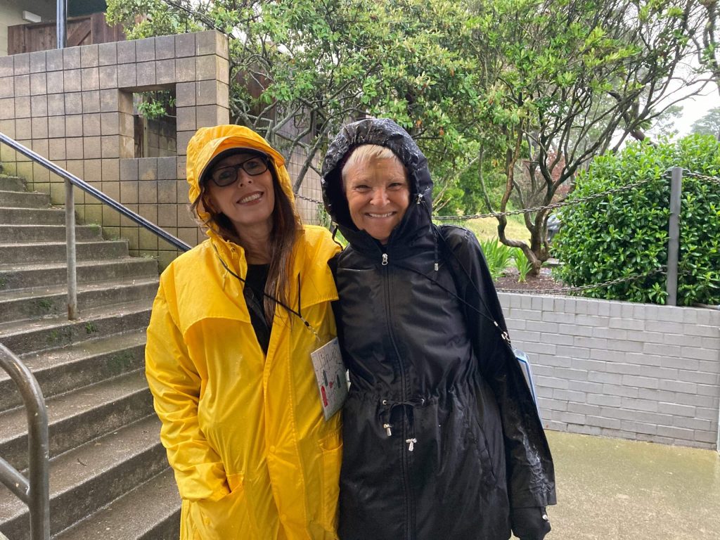 Two individuals wearing raincoats pose for a picture.