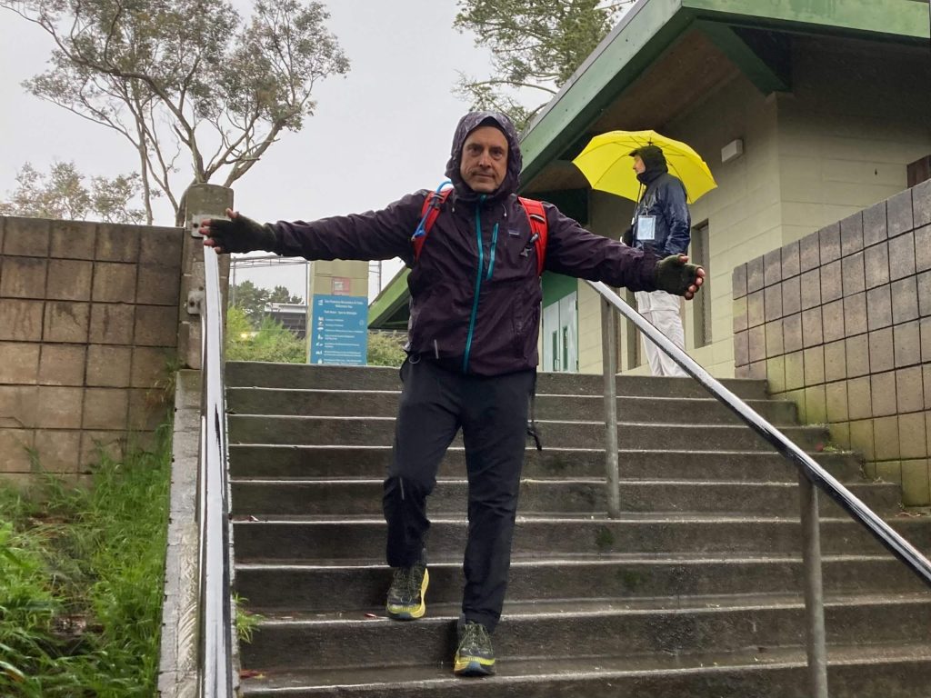 An individual walking down a flight of stairs with their arms outstretched.