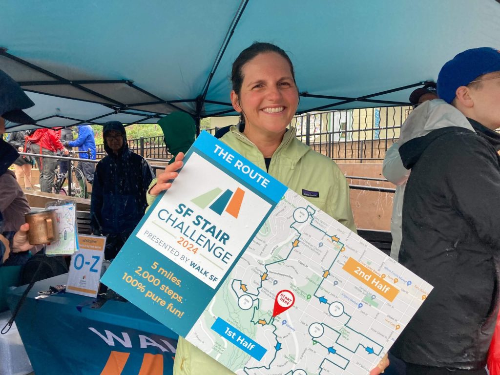 An individual wearing a green raincoat hold up a map.