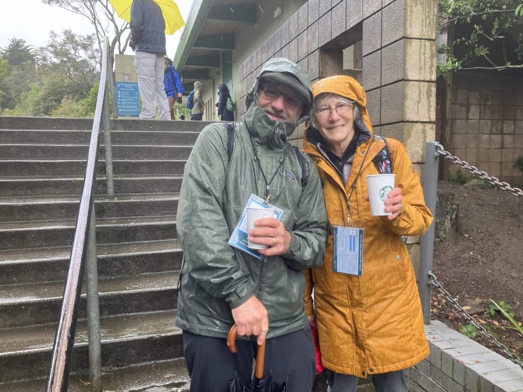 Two individuals pose side-by-side while donning raincoats.